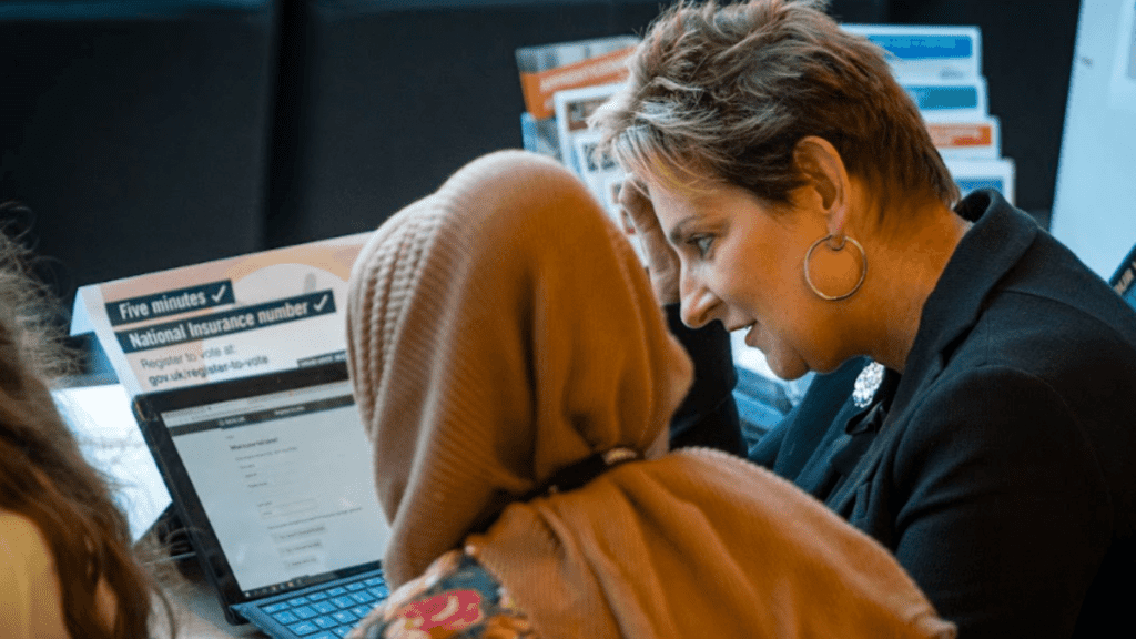 Teacher helping student on computer.